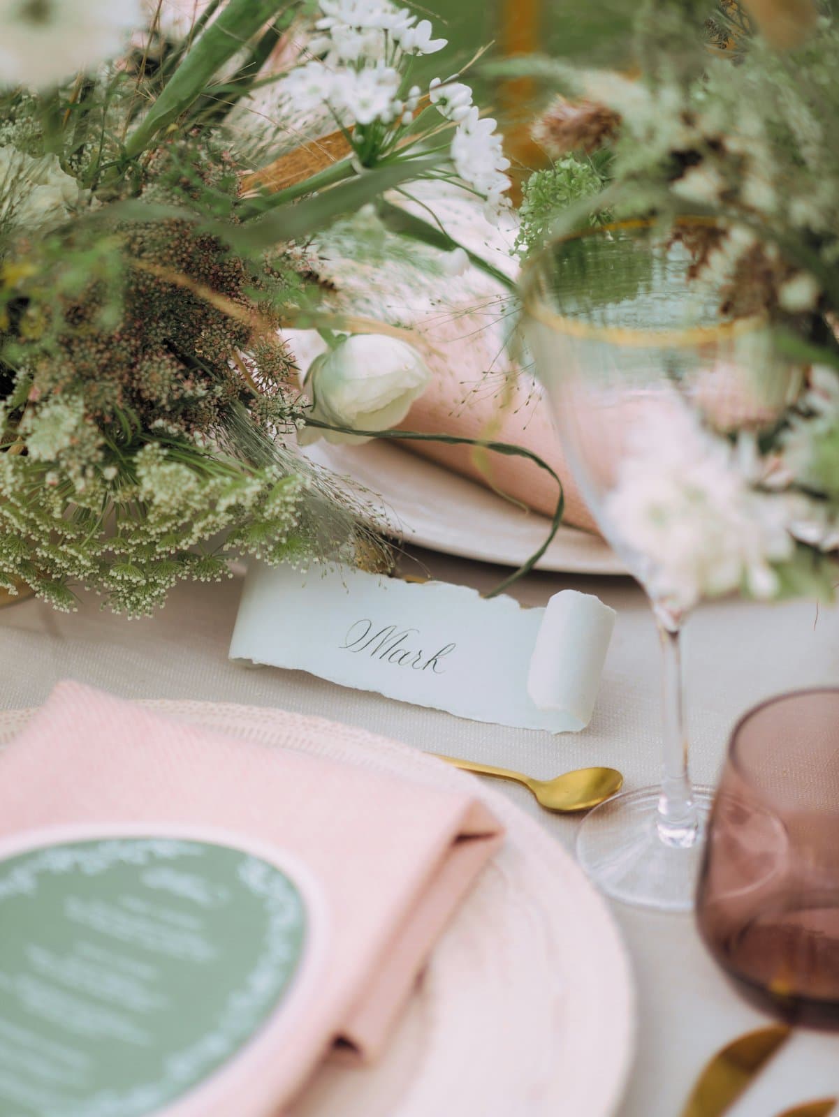 A candlelit wedding reception table set with flowers and place cards